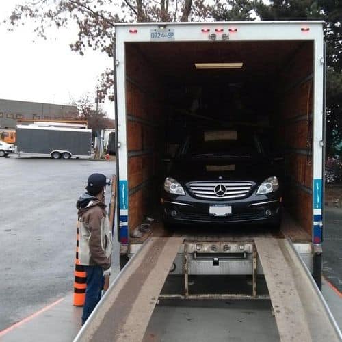 Mercedes-Benz being loaded into a truck at parking lot.