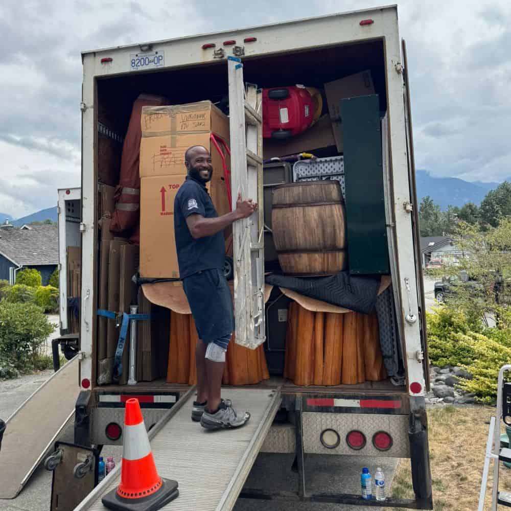 Smiling man unloading moving truck outdoors.