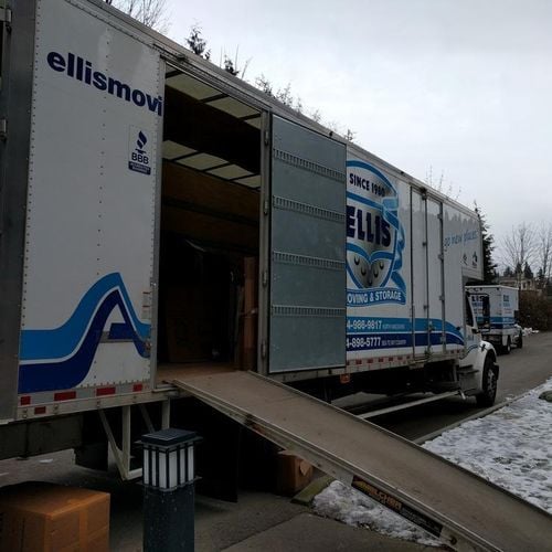 Open moving truck with ramp on snowy street.