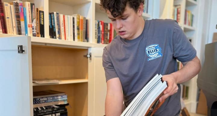 Person organizing books on a bookshelf.