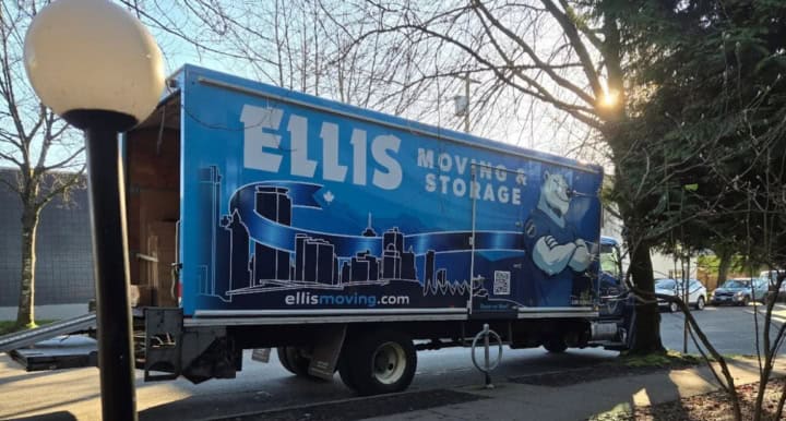 Ellis Moving truck parked on street with trees.