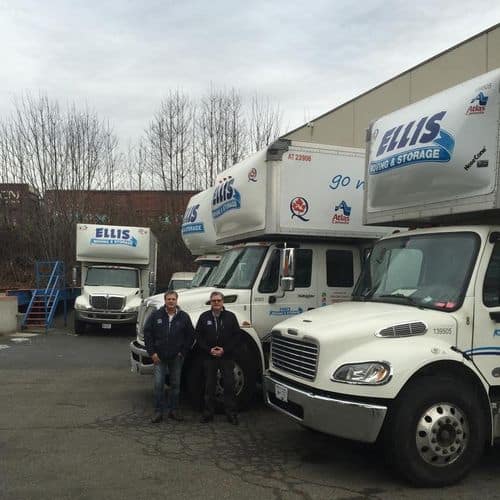 Ellis moving trucks parked with two people standing.