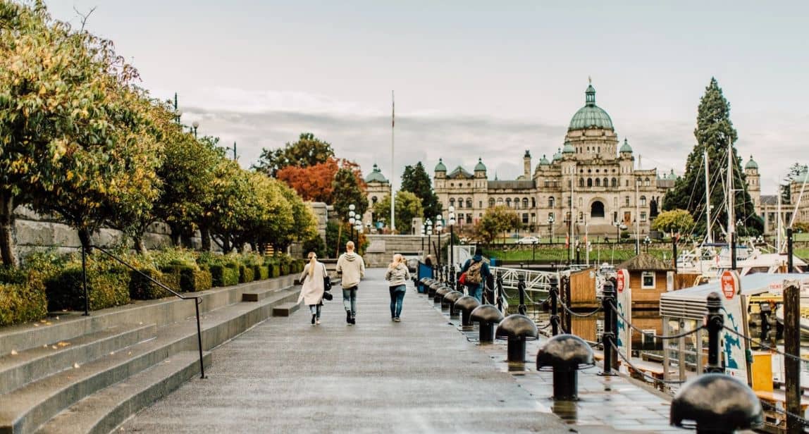 People walking by waterfront, historic building in background